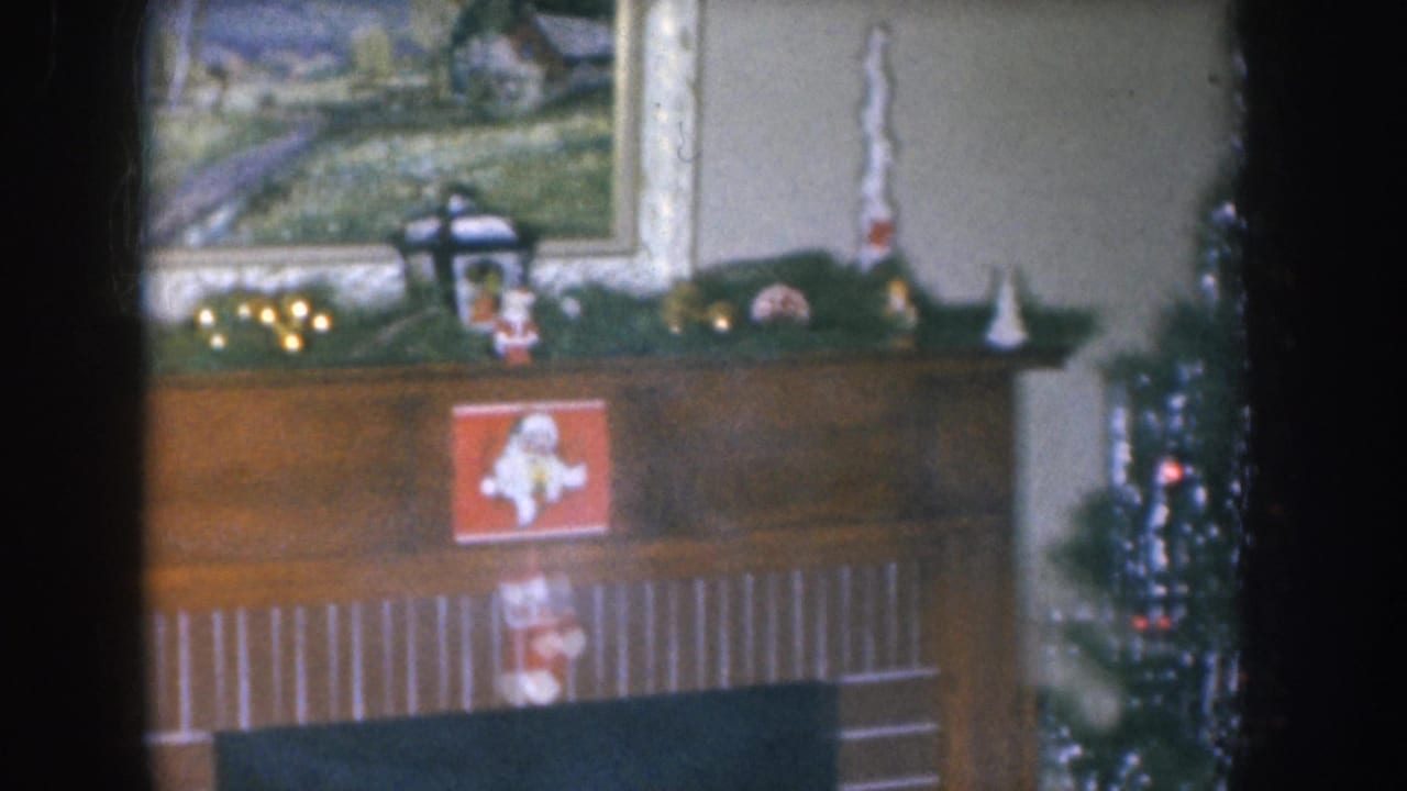 Wooden fireplace mantel with a framed landscape painting above, Christmas garland, small decorations, and a Santa Claus card in the firebox area.