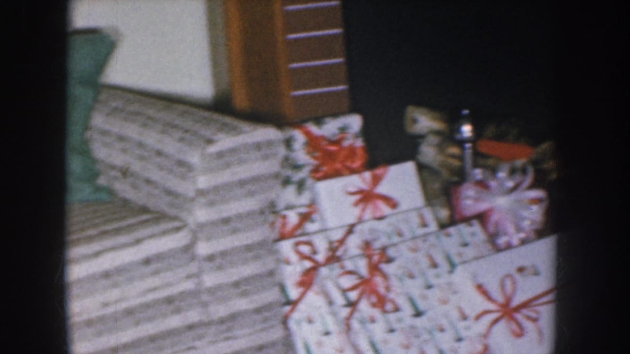 Wrapped Christmas gift stack with striped paper and red ribbon bows filmed on 8mm, Nebraska home movie circa 1955.