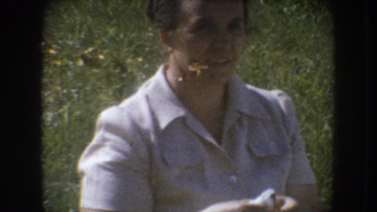 Mid-1950s woman in white collared shirt smiling at camera in outdoor grassy setting, South Dakota; characteristic 8mm film gate vignetting visible.