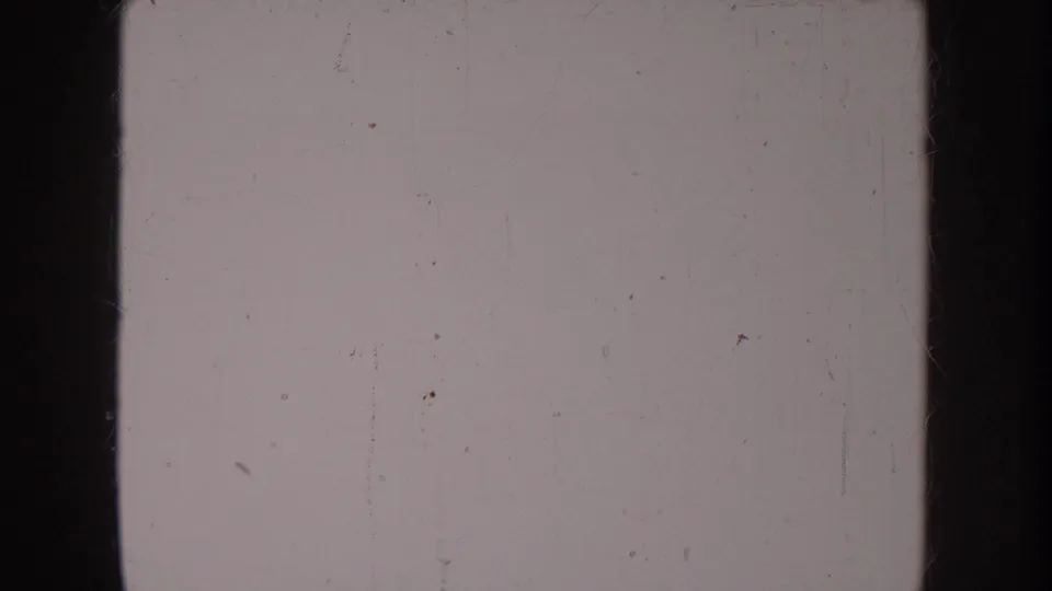 Terminal section of aged 8mm film, largely blank and overexposed, with light scratches and dust marks on the emulsion surface — no subject matter legible.