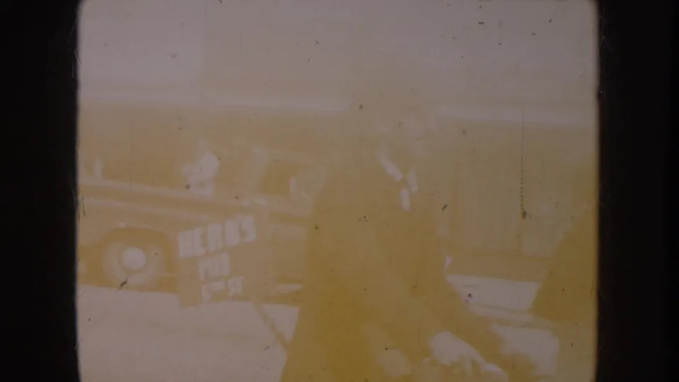 Overexposed opening frame from a circa-1955 8mm home movie; faint outlines suggest an outdoor street setting; detail lost to film burn.