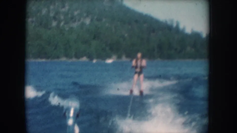 Close view of water skier in swimsuit and life vest on a lake in South Dakota, circa 1956, filmed on 8mm from the tow boat