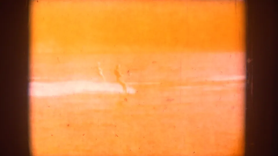 Light-struck 8mm frame showing total orange overexposure and a bright horizontal streak, likely a splice or reel-change artifact; no recoverable scene detail.