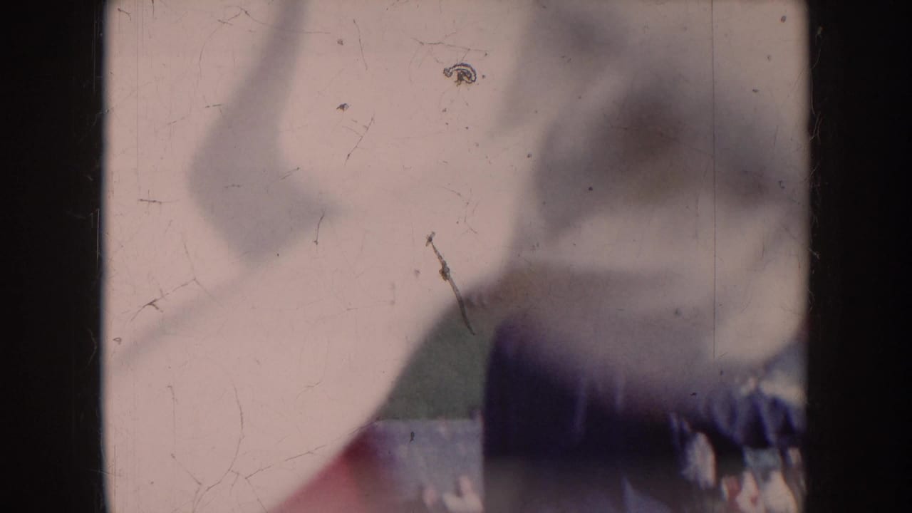First frame of 1957 Nebraska amateur football 8mm footage, mostly obscured by an object close to the lens, with film scratches and pale overexposure.