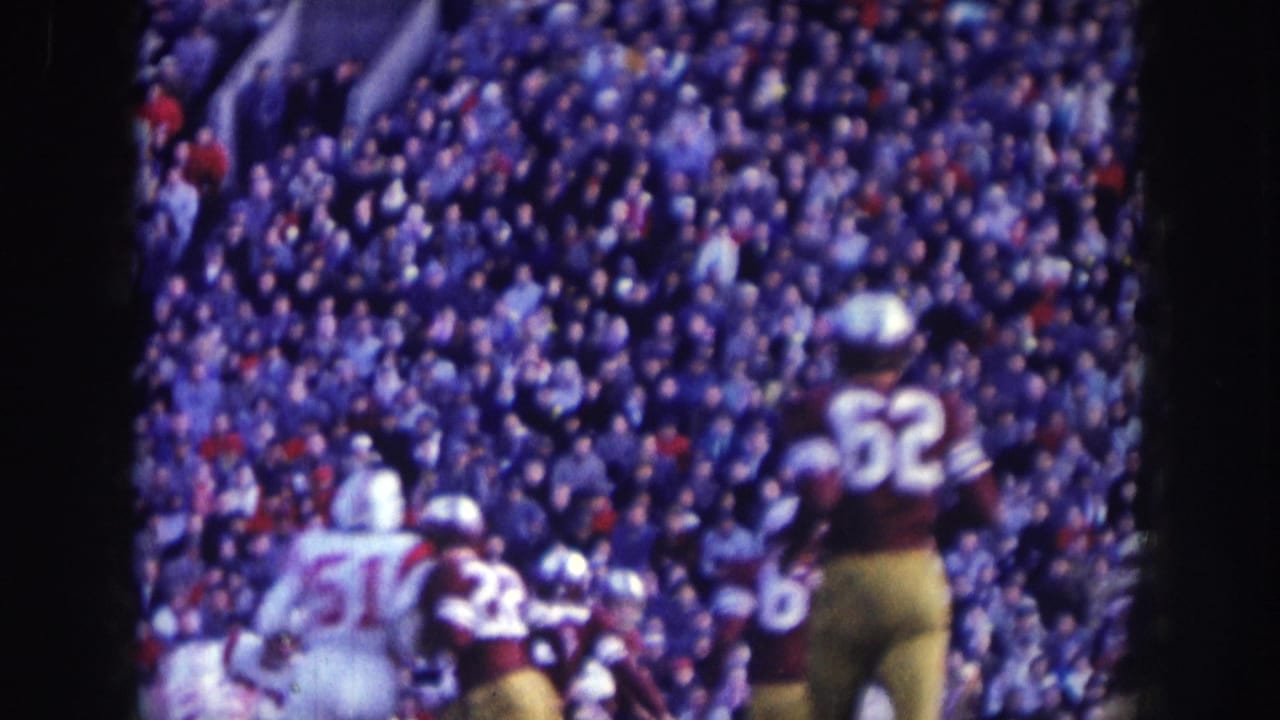 Two players in contrasting uniforms: no. 62 in white and a dark-uniformed opponent, with a packed stadium crowd behind.