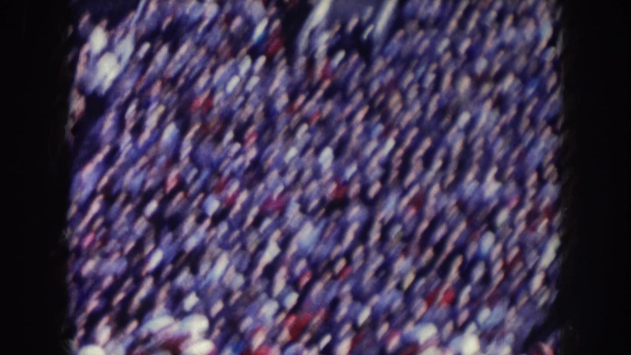 Packed stadium crowd in tiered bleachers filmed on 8mm, consistent with a late-1950s Nebraska stadium event.