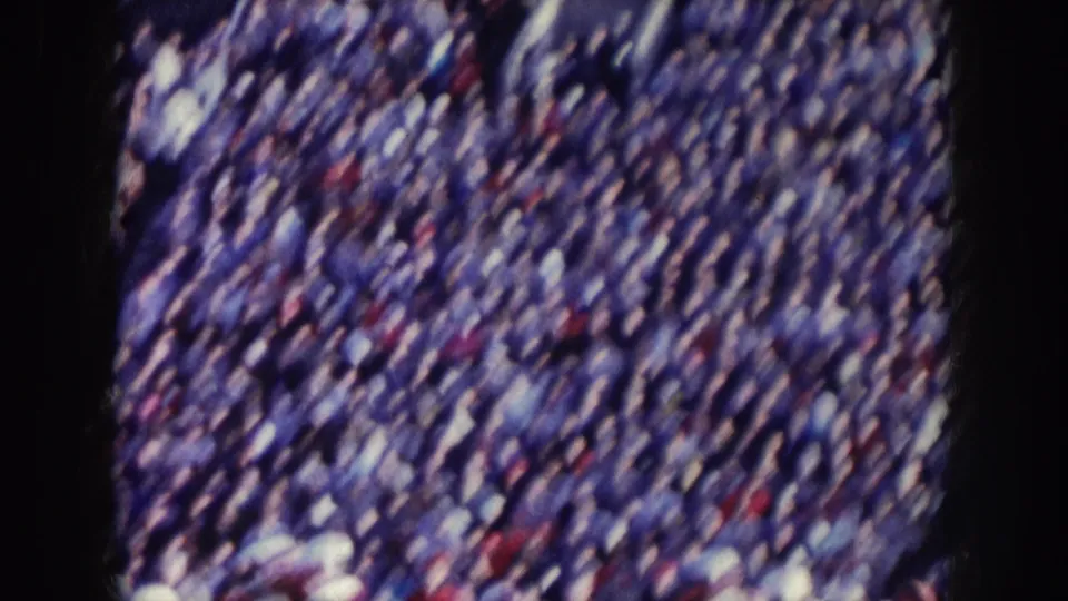 Packed stadium crowd in tiered bleachers filmed on 8mm, consistent with a late-1950s Nebraska stadium event.