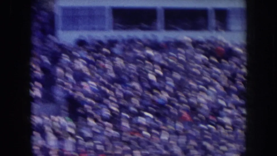 Packed stadium bleachers with upper stadium structure above filmed on 8mm, consistent with a 1950s Nebraska sporting event.
