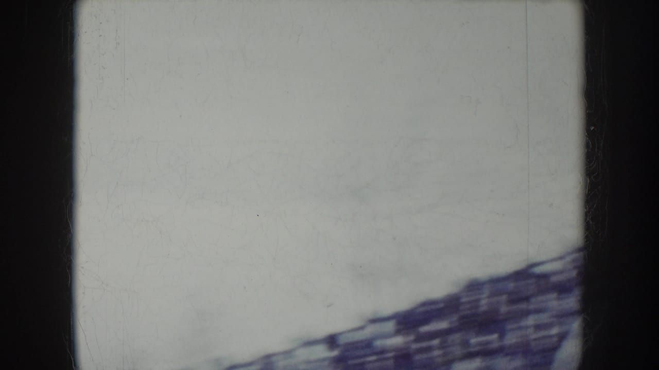 Camera pan sweeps through open sky during the 8mm stadium sequence, leaving a near-blank frame with a sliver of stand structure at the base.