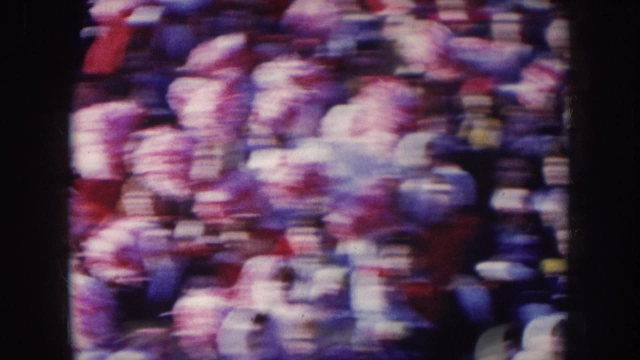 Wide crowd shot showing hundreds of stadium spectators in red and white winter clothing and hats.