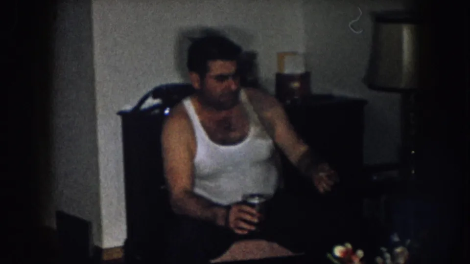 Man in white undershirt at rest in a 1950s home interior; cigarette smoke trail visible in mid-air, beverage can held in hand.
