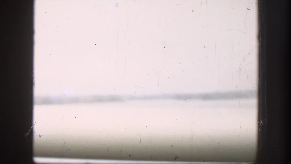 Washed-out 8mm frame from a 1958 river-crossing sequence — faint horizontal lines suggest bridge structure or sky, with severe overexposure throughout.