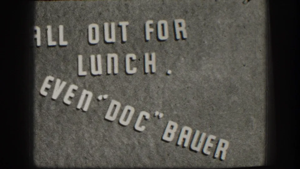 8mm color close-up of a mid-century informal business sign in white stenciled lettering on textured concrete, Kansas, circa 1958.