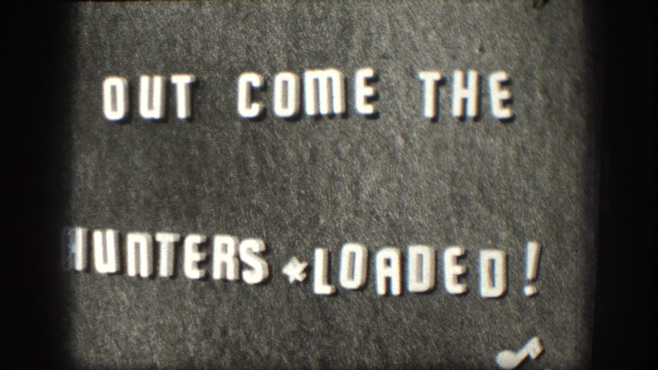 8mm home-movie title card circa 1958: 'OUT COME THE HUNTERS * LOADED!' in hand-set block letters on dark board, likely a chapter opener for a Kansas hunting-trip reel.