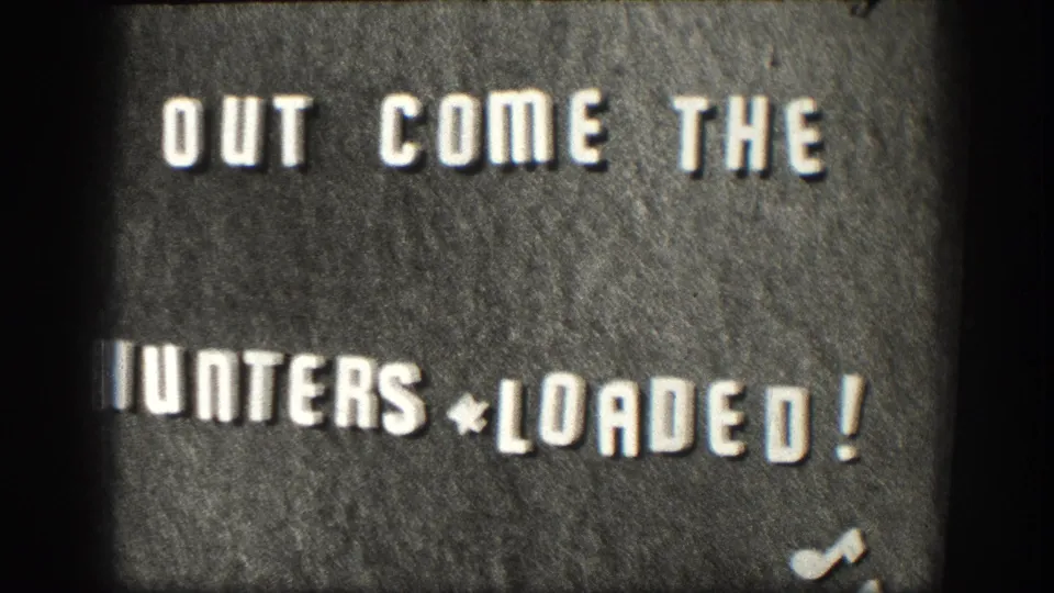 Closing frame of an 8mm hunting-trip title card circa 1958, reading 'OUT COME THE HUNTERS * LOADED!' — Kansas home movie, consistent exposure and grain throughout.