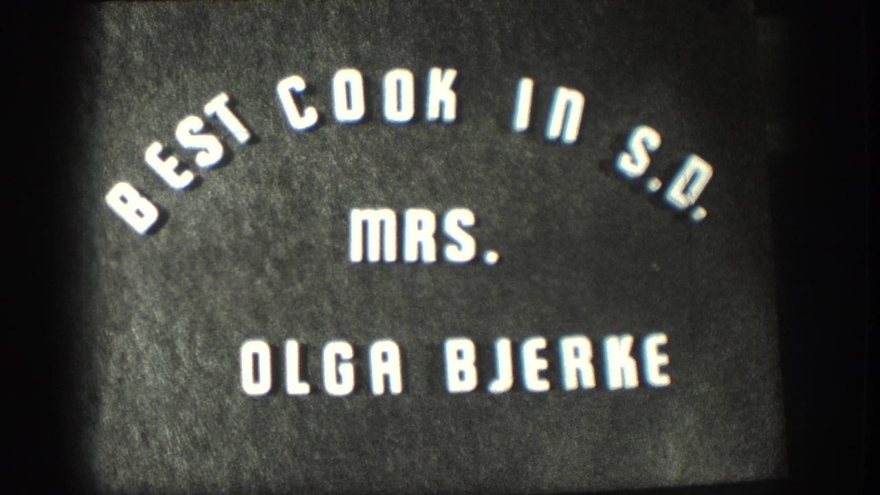 8mm home-movie title card circa 1958 identifying Mrs. Olga Bjerke as best cook in S.D., white stylized lettering on a dark field.