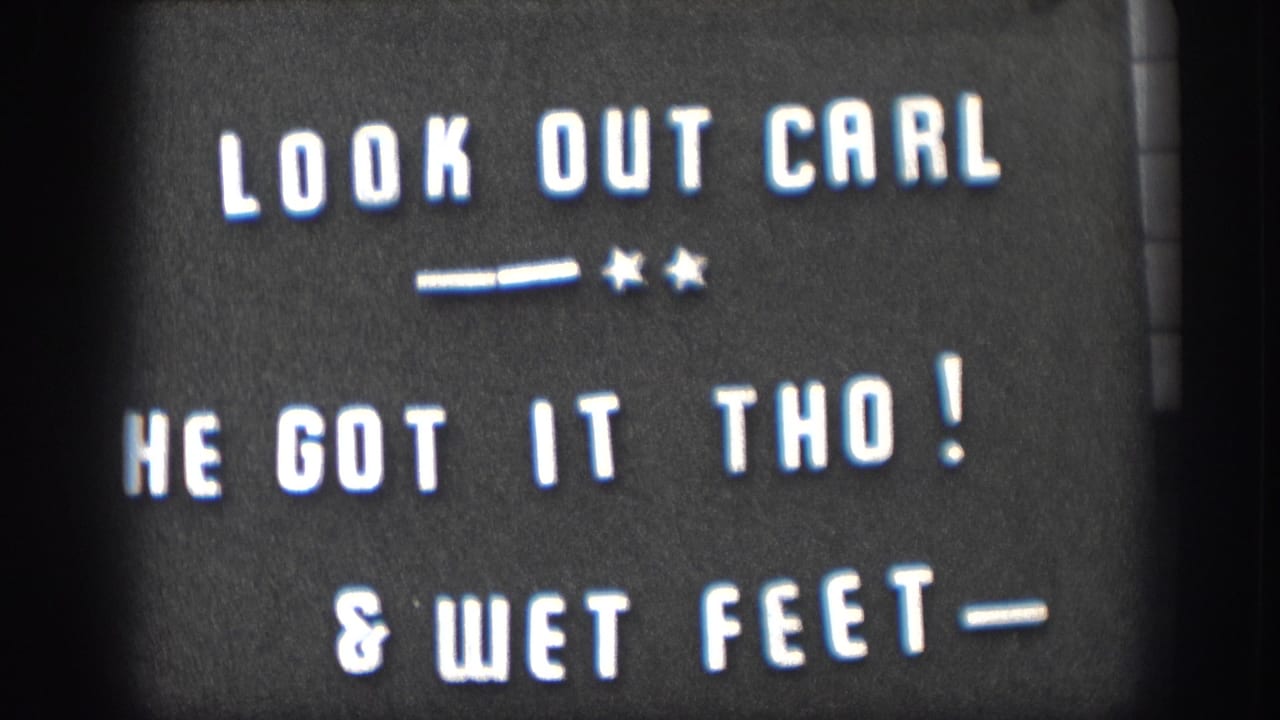 Held 8mm intertitle card at clip end: 'LOOK OUT CARL / HE GOT IT THO! / & WET FEET-'; white hand-lettered text on dark ground with decorative stars and dashes.