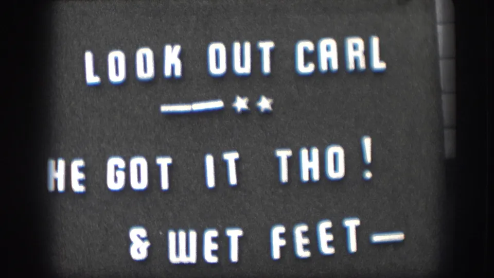 Held 8mm intertitle card at clip end: 'LOOK OUT CARL / HE GOT IT THO! / & WET FEET-'; white hand-lettered text on dark ground with decorative stars and dashes.