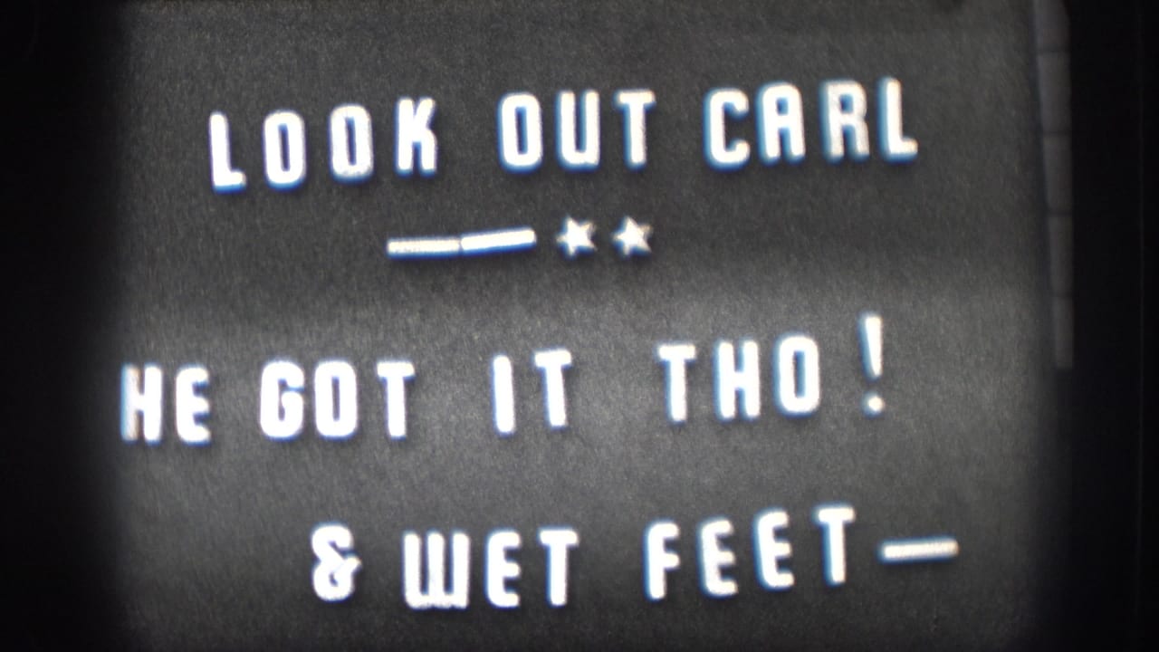 1958 Kansas home movie intertitle: LOOK OUT CARL, HE GOT IT THO!, and WET FEET, white hand-lettered text on black card with star-dash flourish.