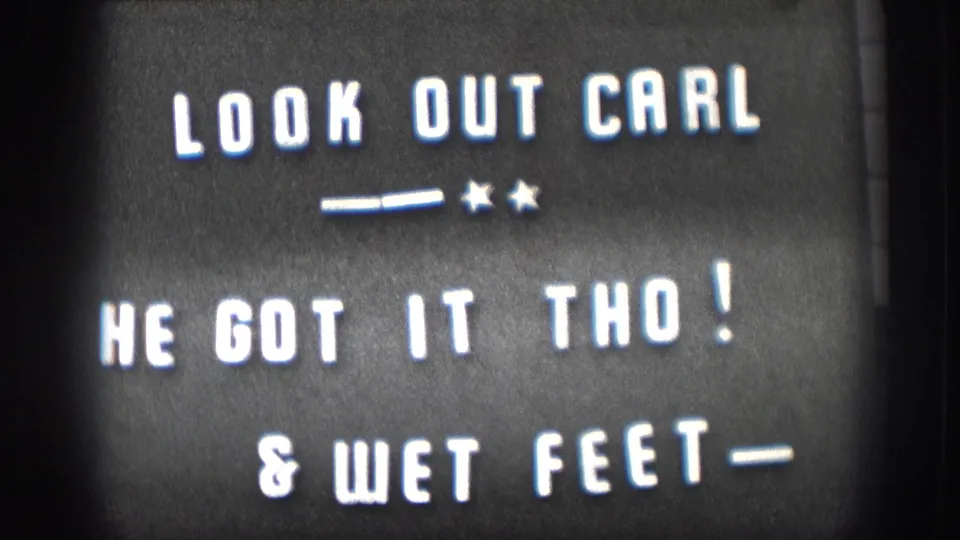 1958 Kansas home movie intertitle: LOOK OUT CARL, HE GOT IT THO!, and WET FEET, white hand-lettered text on black card with star-dash flourish.