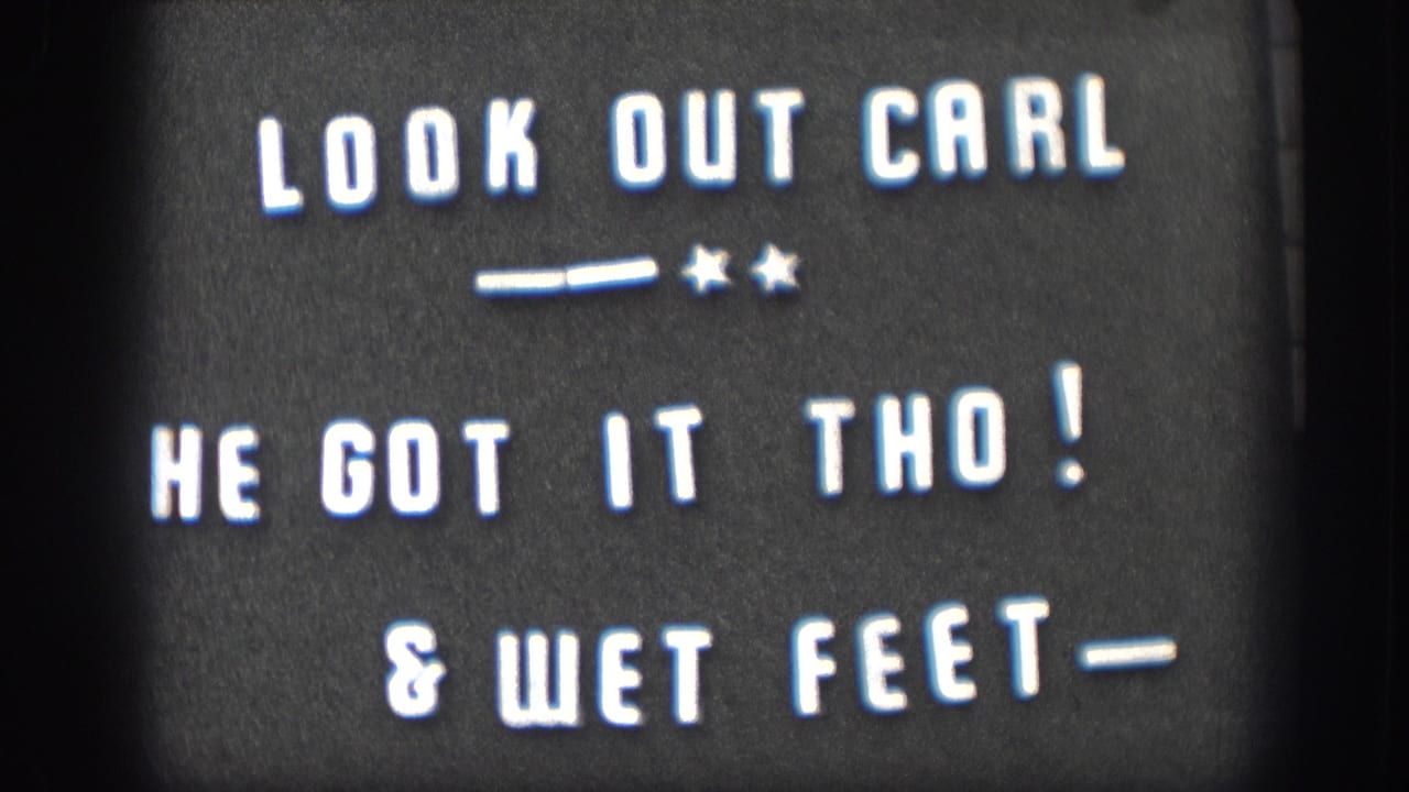 Continued hold on the 1958 Kansas home movie intertitle card, white text on black reading LOOK OUT CARL, HE GOT IT THO!, and WET FEET.