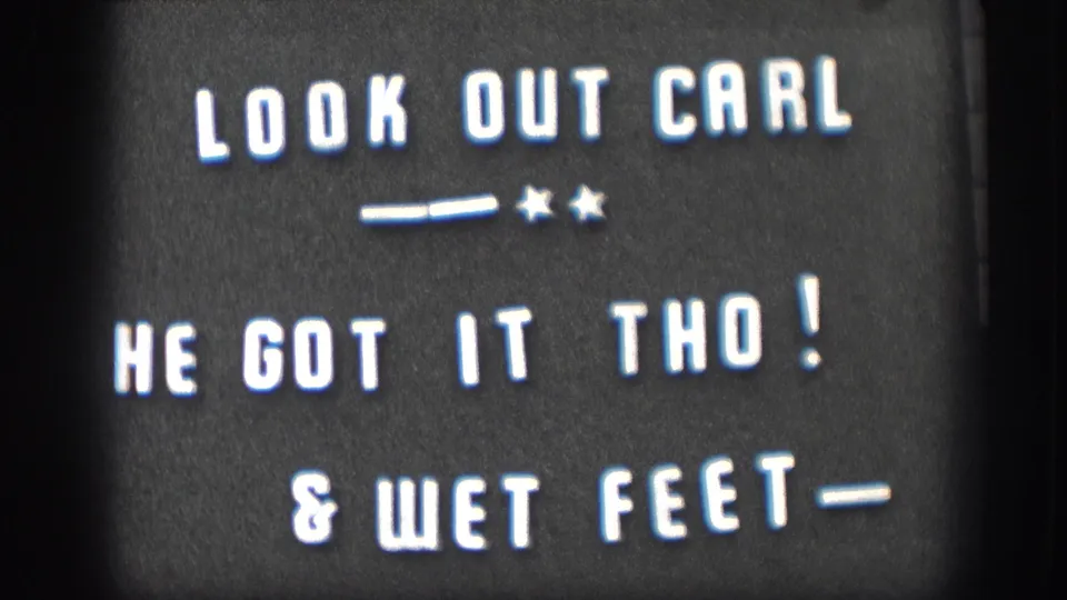 Continued hold on the 1958 Kansas home movie intertitle card, white text on black reading LOOK OUT CARL, HE GOT IT THO!, and WET FEET.