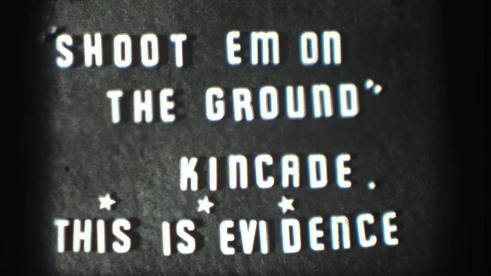 Hand-lettered home-movie title card: 'SHOOT EM ON THE GROUND / KINCADE / THIS IS EVIDENCE'; consistent with 1950s amateur film titling.