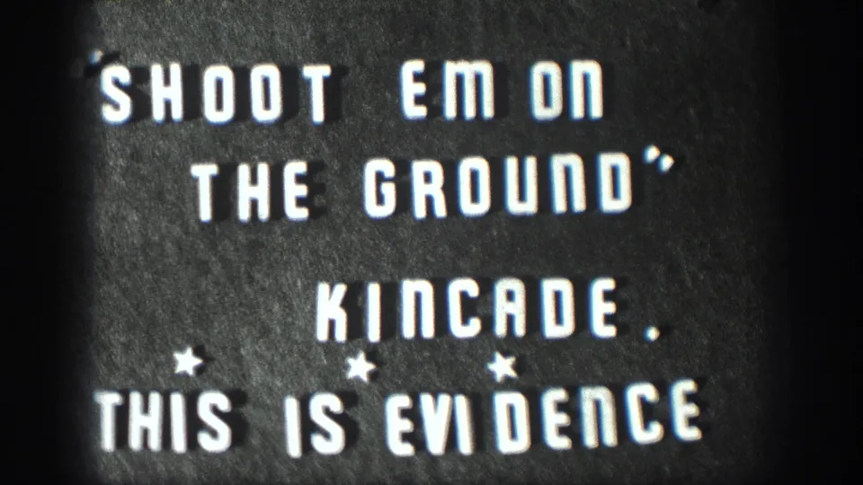 1958 Kansas 8mm home movie title card; white stencil letters on dark board read SHOOT EM ON THE GROUND, KINCADE, THIS IS EVIDENCE with three small star ornaments