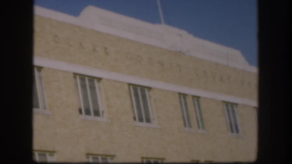 Close upward-angle view of Clark County Courthouse engraved upper facade and roofline against clear blue sky, Kansas circa 1958, 8mm color film.