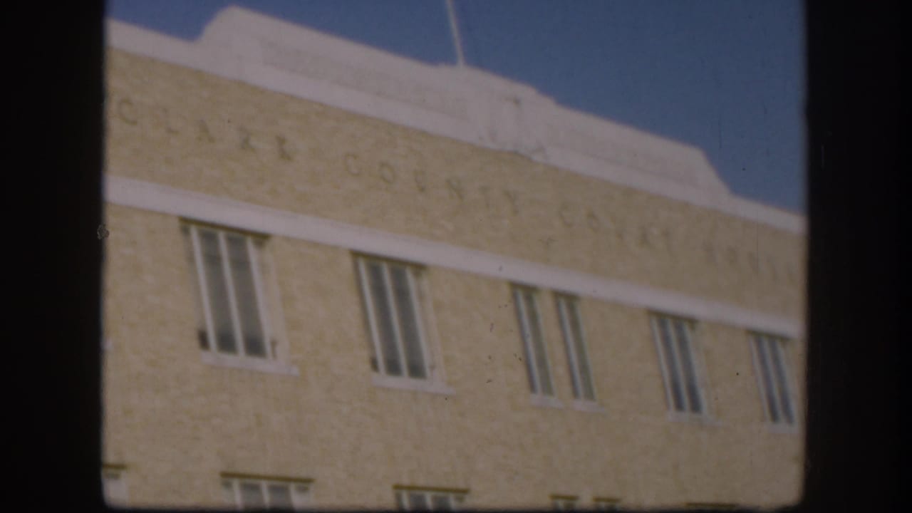 Continuing low-angle shot of the Clark County Courthouse cream brick facade; engraved name and upper windows remain visible with similar framing.