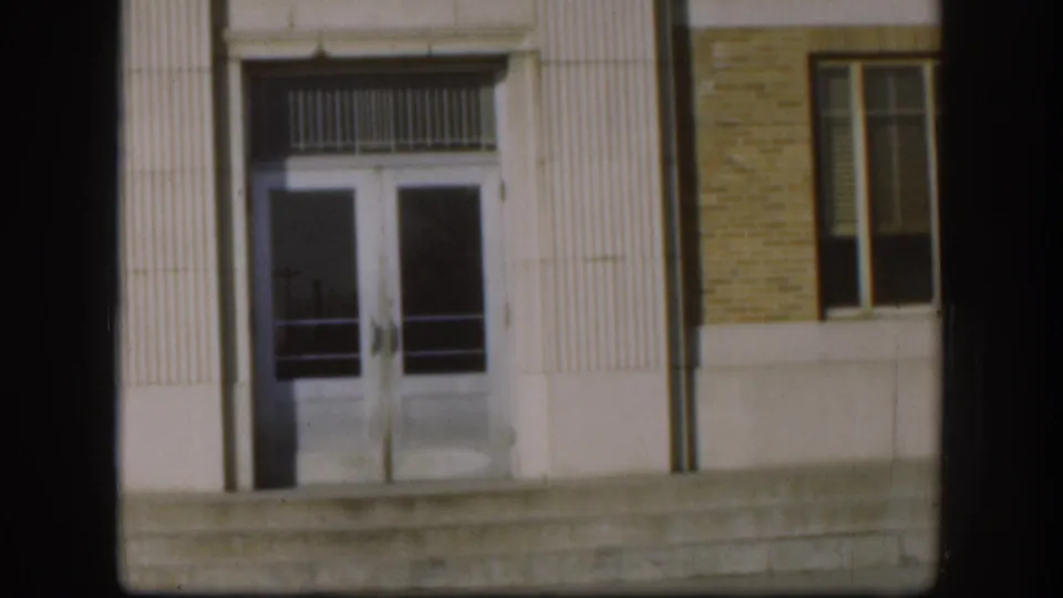 Clark County Courthouse entrance detail, Kansas, 1958 — 8mm framing of double glass doors, decorative transom, fluted columns, and flanking ground-floor window.