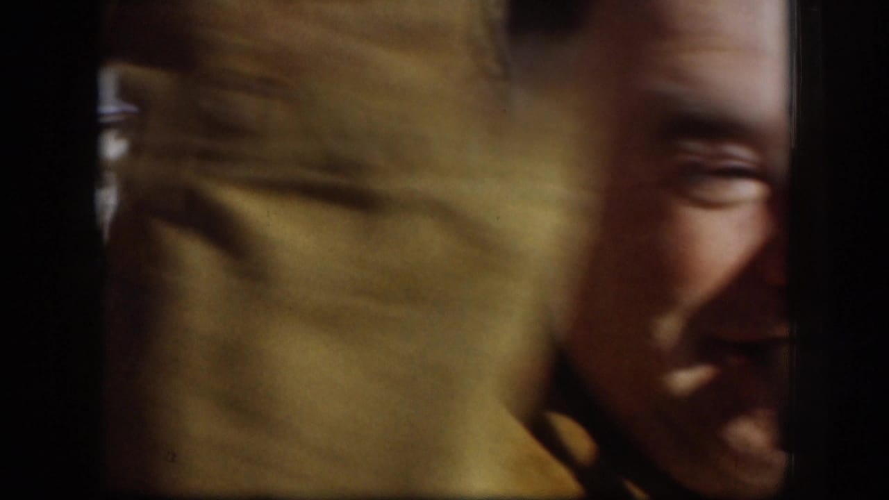Extreme close-up of an adult male face, motion-blurred from a camera pan, warm amber tones distinct from the blue cast of the frames that follow.