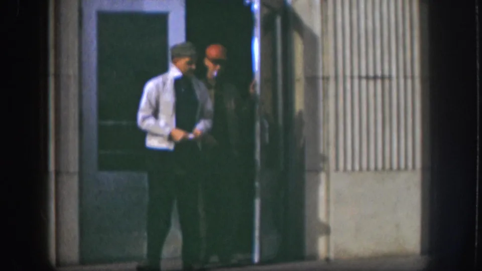 Two men standing outside a mid-century institutional building with ribbed cladding, Kansas, circa 1958; glass door visible in background.