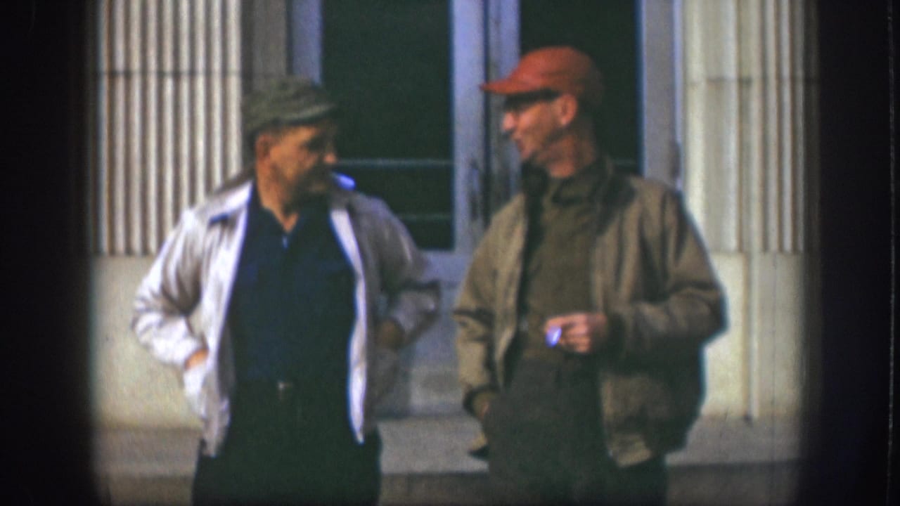 Two adult men in late-1950s casual workwear conversing outside a columned institutional building, Kansas USA, circa 1958.