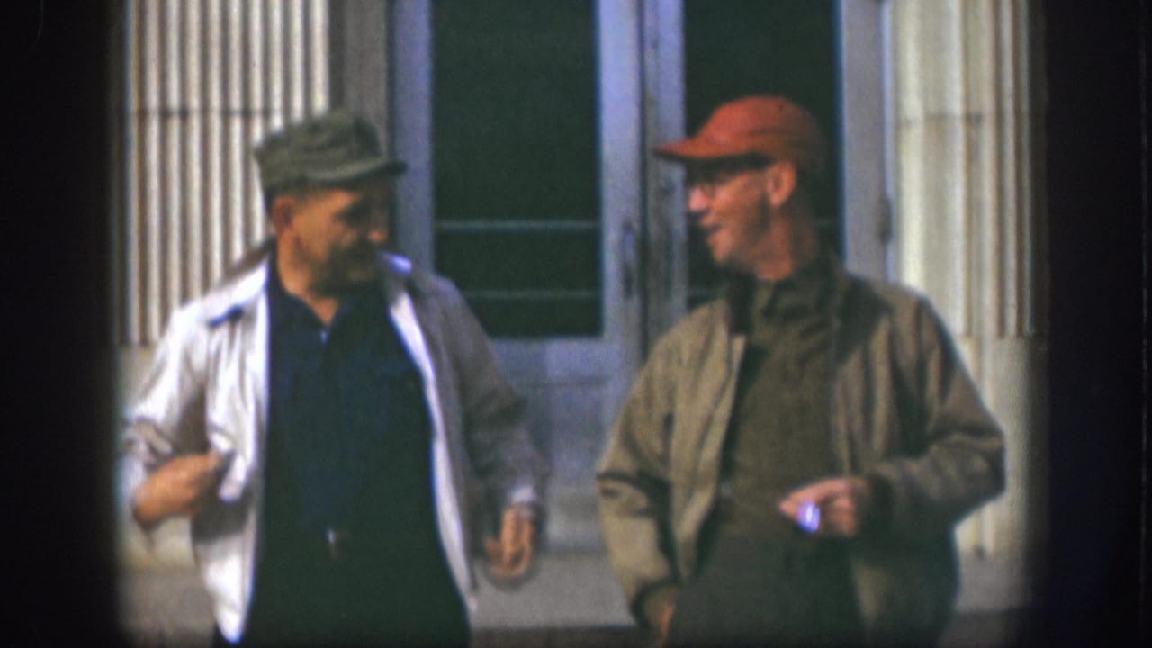 Two adult men sharing a laugh outside a fluted-column building facade, Kansas USA, circa 1958.