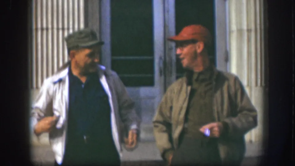 Two adult men sharing a laugh outside a fluted-column building facade, Kansas USA, circa 1958.