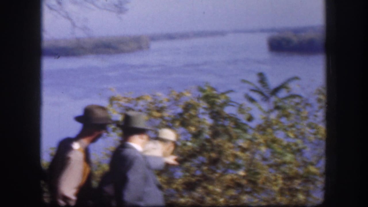 Two men wearing brimmed hats and jackets stand at an elevated overlook gazing toward a wide river with tree-covered islands, Kansas, USA, circa 1958.
