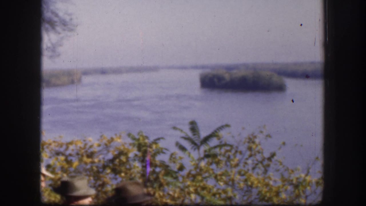 Broad river landscape with tree-covered islands shot from elevated overlook; a partial figure in a brimmed hat is just visible at the lower frame edge, Kansas, USA, circa 1958.