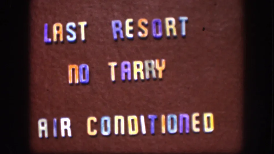 8mm home movie still of a mid-century roadside changeable letter board advertising air-conditioned lodging, Kansas, circa 1958; same sign composition as prior frames.