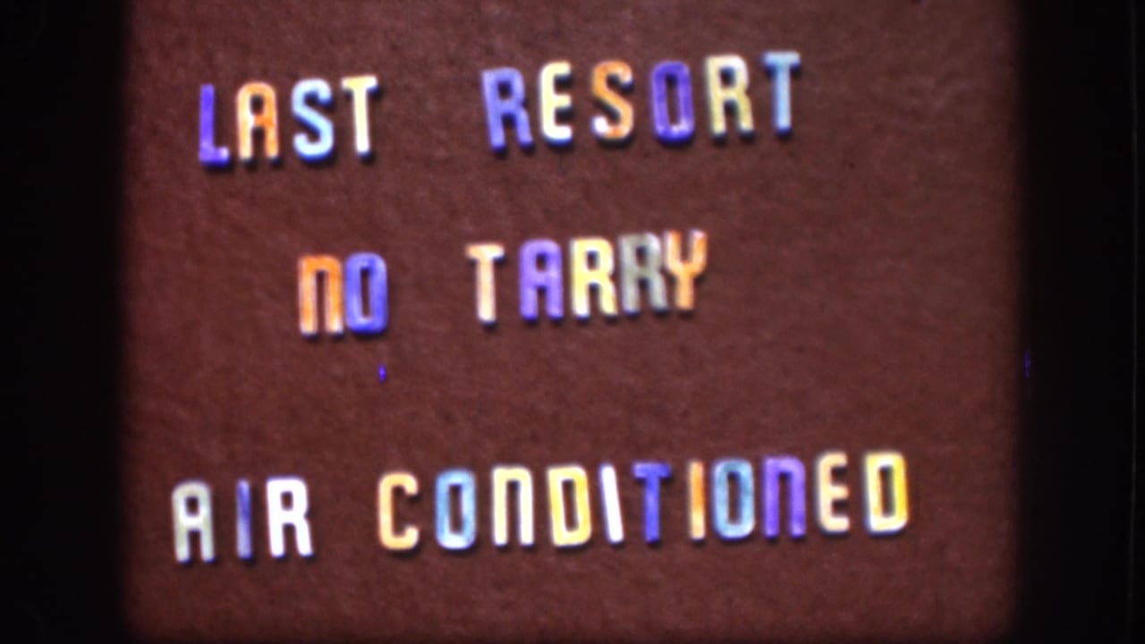 Same three-line roadside sign 'LAST RESORT / NO TARRY / AIR CONDITIONED' on brown wall, steady 8mm shot with rainbow-tinted lettering.