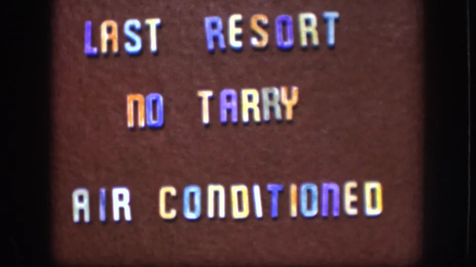 Closing 8mm frame c. 1958 Kansas of a roadside establishment sign; letter color shift and dark film border consistent with 8mm reversal stock.