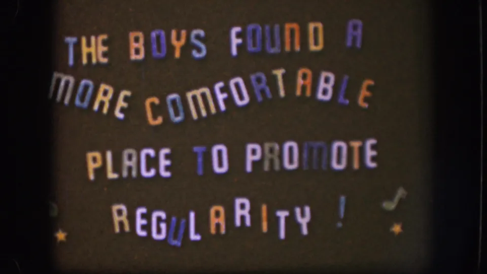 Full view of a 1958 home-movie intertitle card with whimsical multicolored hand-lettered text, musical notes, and star decorations on a dark field.