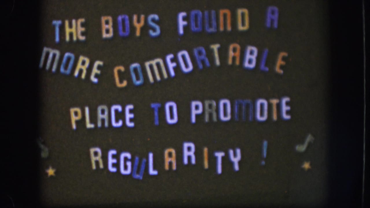 Multicolored hand-lettered title card reading 'THE BOYS FOUND A MORE COMFORTABLE PLACE TO PROMOTE REGULARITY!' on a dark background with musical notes and stars.