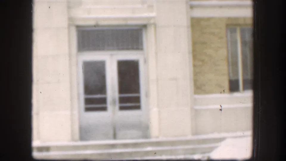 Stone facade and double-door entrance of an institutional building with snow at the base, consistent with a Kansas winter setting circa 1958.