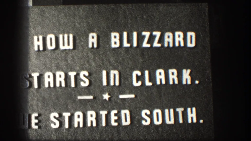An 8mm home-movie title card reading 'HOW A BLIZZARD STARTS IN CLARK. — ★ — WE STARTED SOUTH.' narrates the filmmaker's departure from a Kansas winter storm, circa 1958.