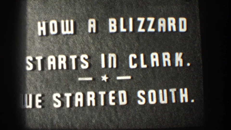 8mm intertitle card from a 1958 Kansas home movie reading 'HOW A BLIZZARD STARTS IN CLARK. — * — WE STARTED SOUTH.' on dark background.