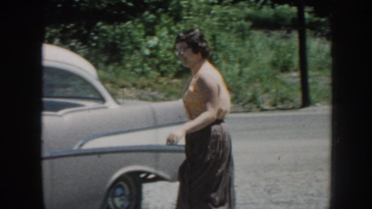 Woman approaching the rear door of a late-1950s American sedan on a gravel driveway, Nebraska, circa 1958, 8mm color home movie.