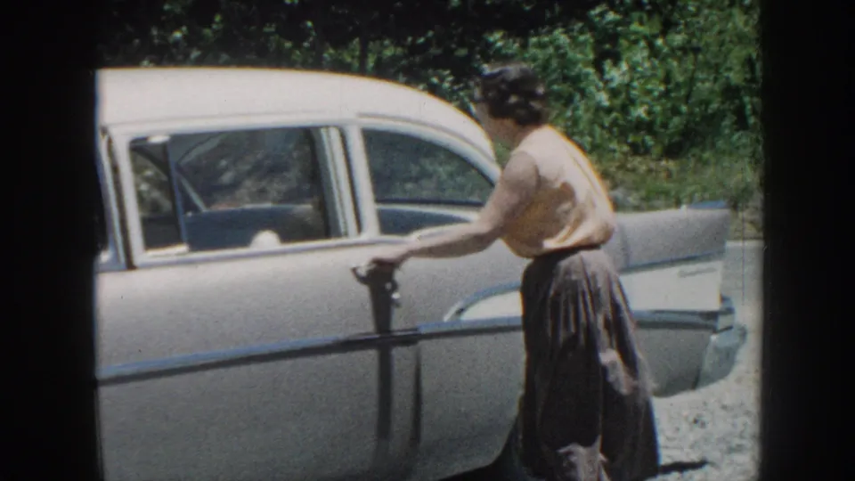 Woman opening the rear passenger door of a late-1950s American sedan, circa 1958 8mm home movie, Nebraska.