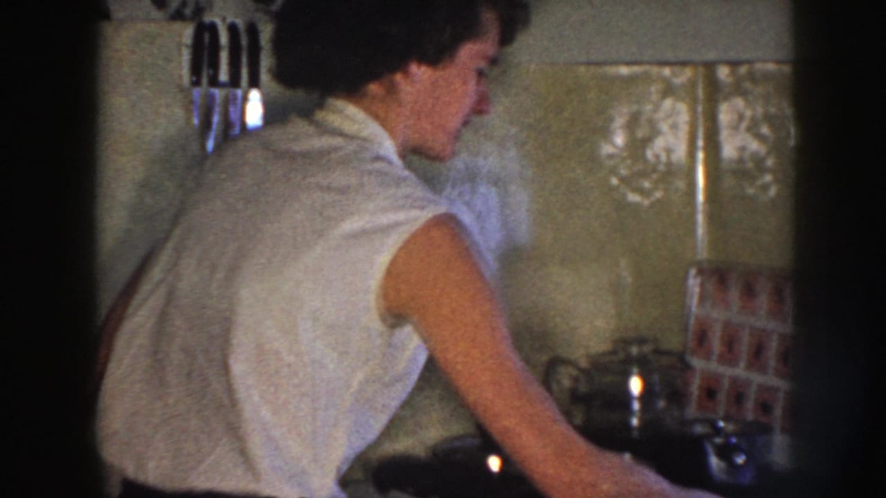 Woman in a sleeveless white top working at a kitchen counter.