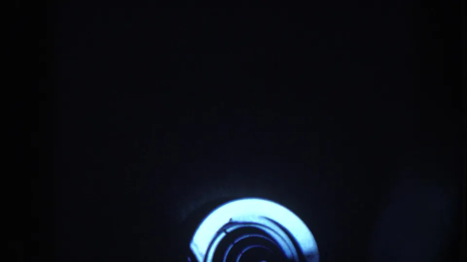 A heavily shadowed 8mm frame shows only a bright circular object near the lower edge, with most interior detail obscured.